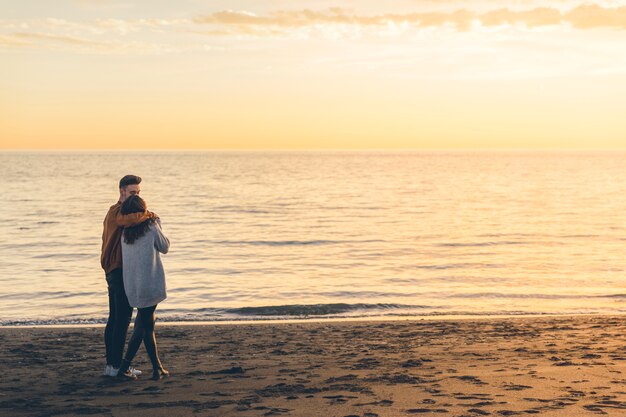 Young couple hugging on sea shore in evening 
