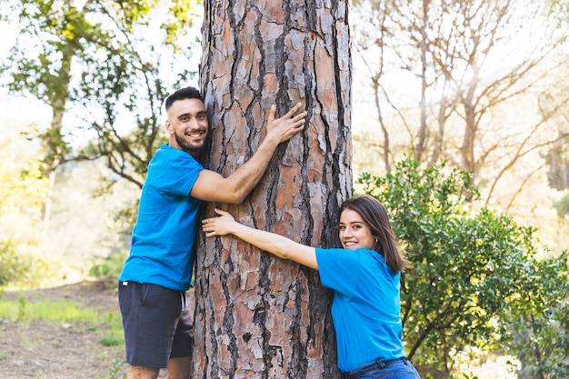 Young couple hugging tree trunk