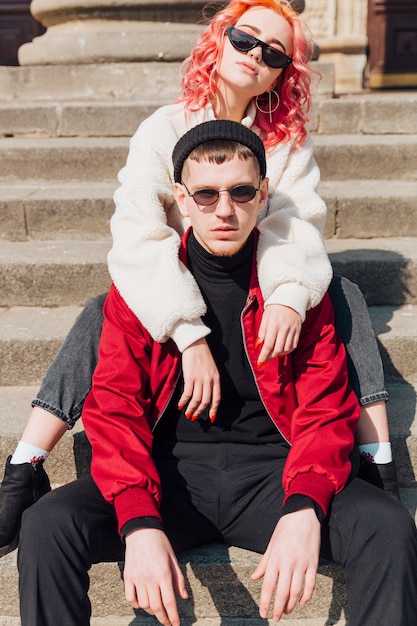 Free photo young couple hugging while sitting on stairs