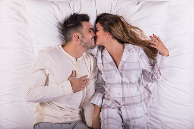 若いカップルがベッドの中でキス