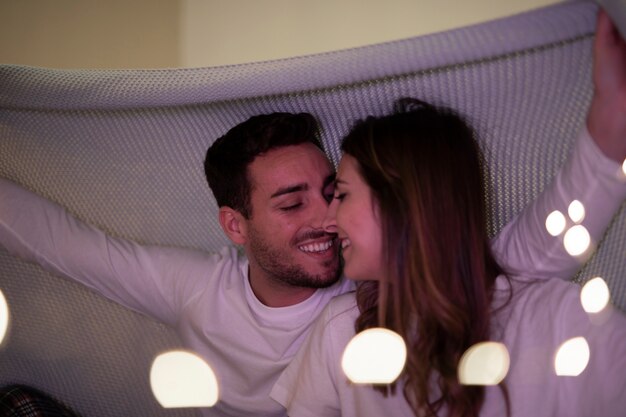 Young couple kissing under blanket