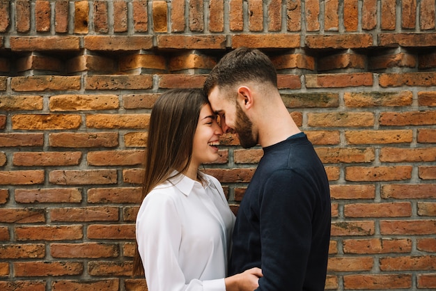 Free photo young couple kissing in front of wall