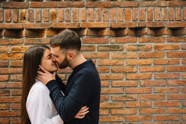 Young couple kissing in front of wall