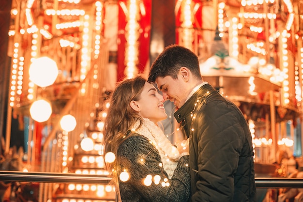 Young couple kissing and hugging outdoor in night street at christmas time
