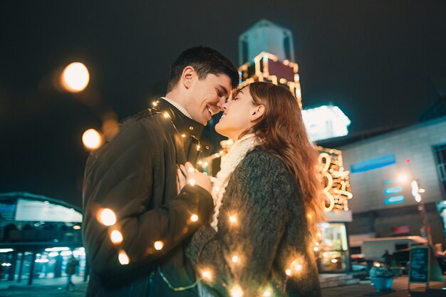 Young couple kissing and hugging outdoor in night street at christmas time