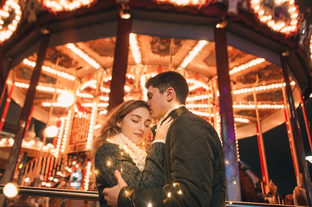 Young couple kissing and hugging outdoor in night street at christmas time