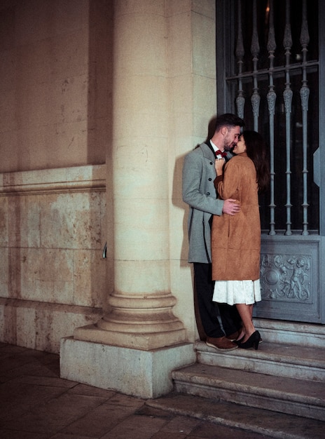 Young couple kissing leaning on wall of building