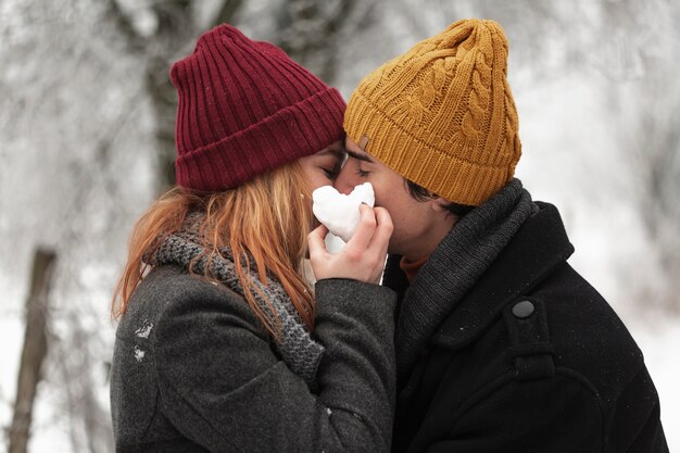 若いカップルが冬のシーズンミディアムショットでキス