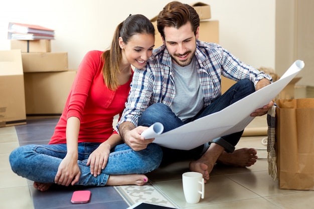 Free photo young couple looking at the blueprints of their new home