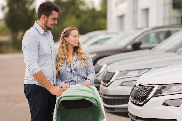 Free photo young couple looking at cars