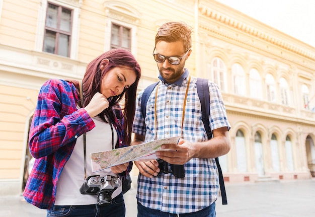 Free photo young couple looking for direction in map