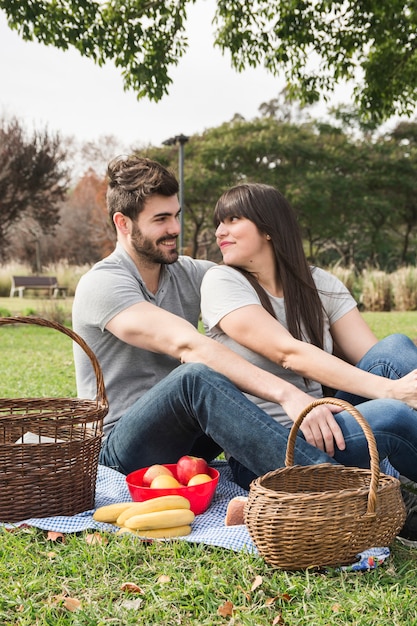 Free photo young couple looking at each other sitting in the park