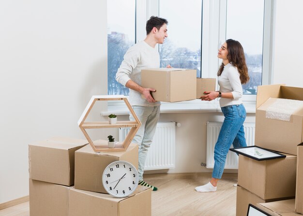 Young couple looking at each other unpacking the moving cardboard boxes at home