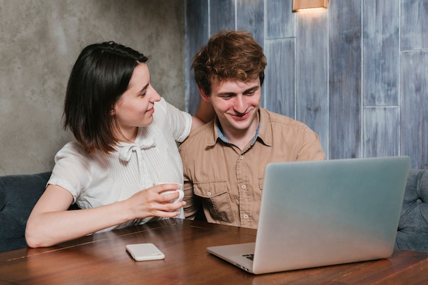 Giovani coppie che esaminano sorridere del computer portatile