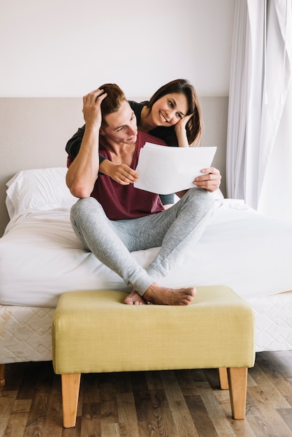 Young couple looking at papers on bed