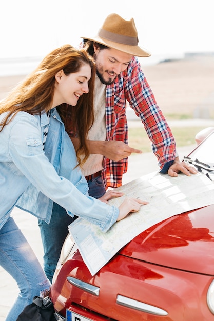 Молодая пара смотрит на дорожную карту на автомобиле
