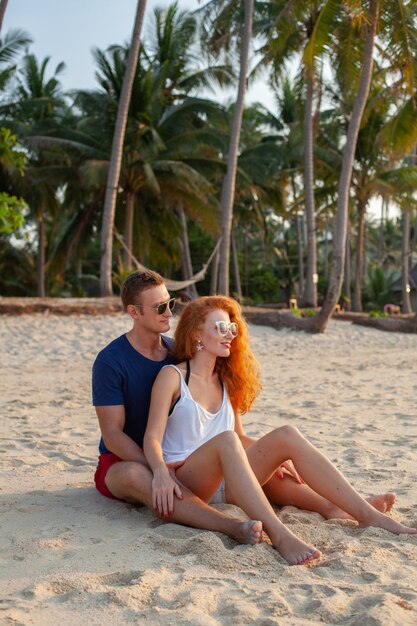 一緒に楽しんで夏のビーチで幸せな恋の若いカップル
