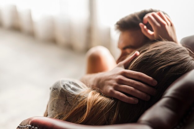 Young couple lying on arm chair loving each other