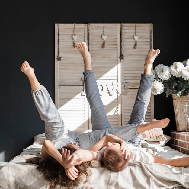 Young couple lying on bed stretching their legs up at home