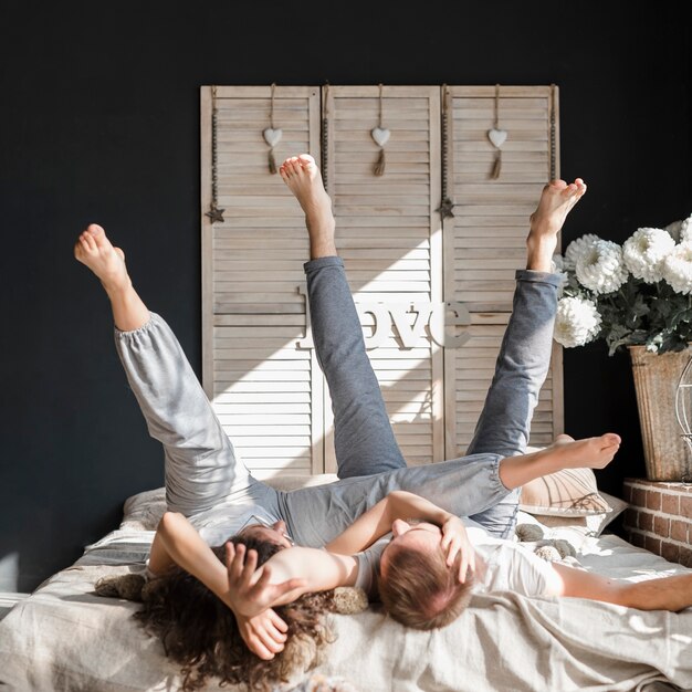 Young couple lying on bed stretching their legs up at home