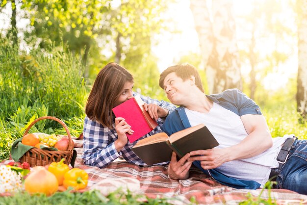 Молодая пара лежит на одеяле и читает книги