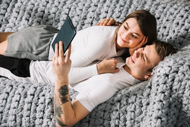 Young couple lying on couch with tablet 