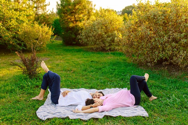 Young couple lying on grass and smiling and touching gently each other