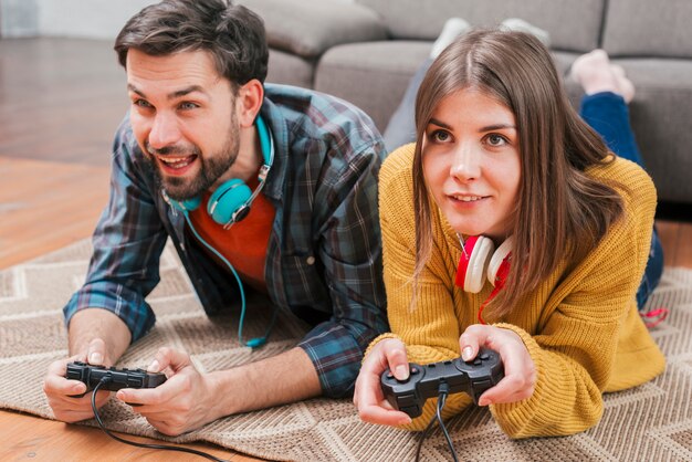 Young couple lying on mat playing the video game