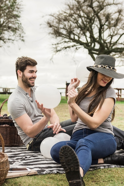 Young couple making fun with white balloons in the park