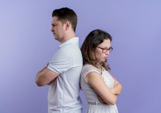 Young couple man and woman back to back frowning over blue