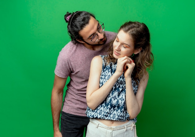 Free photo young couple man and woman happy in love, man going to kiss his shy girlfriend over green background