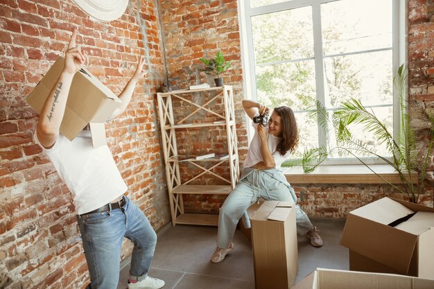 Young couple moved to a new house or apartment. Having fun with cardboard boxes, relaxing after cleaning and unpacking at moved day