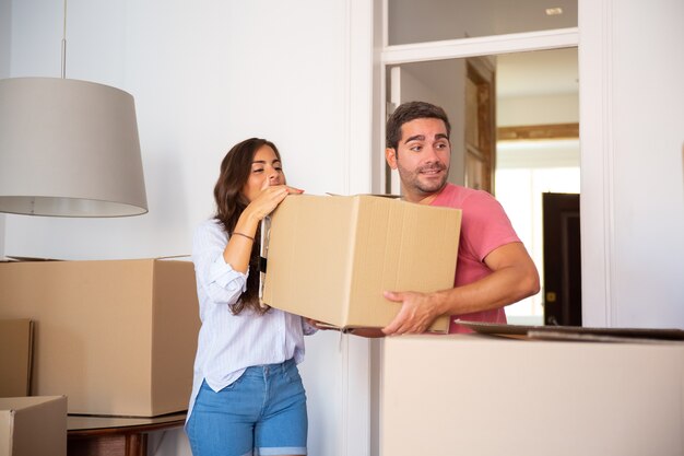 Молодая пара переезжает в новый дом, неся картонные коробки