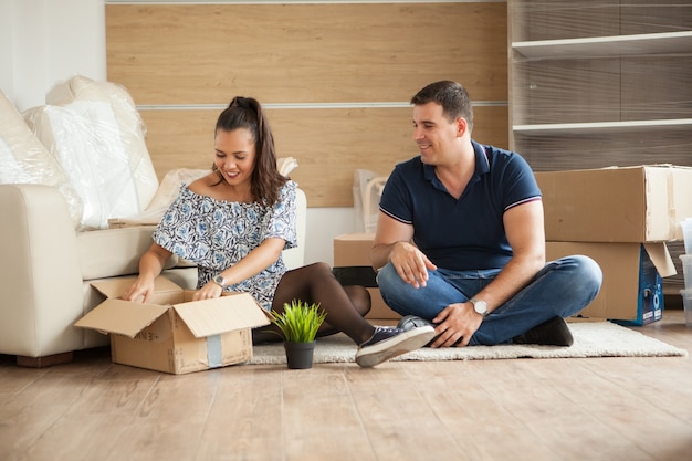 Young couple moving in a new home.Man and woman unboxing fragile stuff.