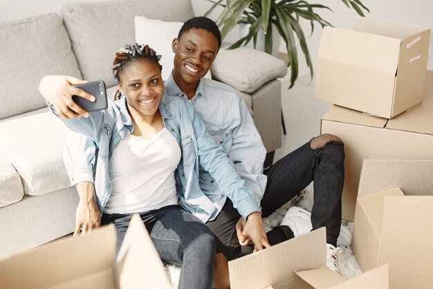 若いカップルが一緒に新しい家に移動します。段ボール箱とアフリカ系アメリカ人のカップル。