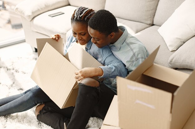 若いカップルが一緒に新しい家に移動します。段ボール箱とアフリカ系アメリカ人のカップル。