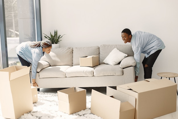 Free photo young couple moving in to new home together. african american couple with cardboard boxes.