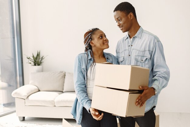 Young couple moving in to new home together. African american couple with cardboard boxes.