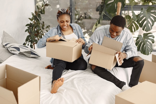 Foto gratuita giovani coppie che si trasferiscono insieme nella nuova casa. coppia afro-americana con scatole di cartone.