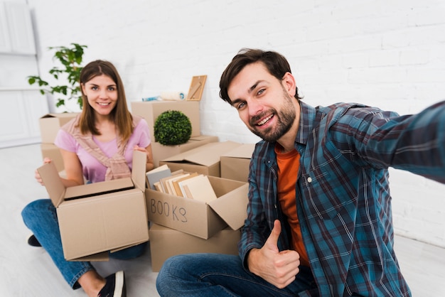 Free photo young couple moving together in new house; unpacking cardboard boxes; taking sulfide