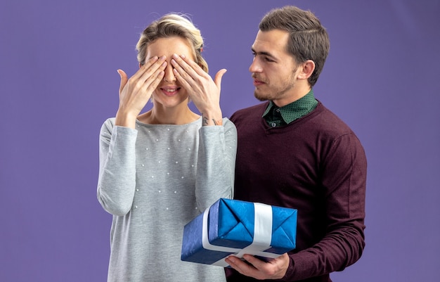 無料写真 バレンタインデーの若いカップルは、青い背景で隔離の女の子にギフトボックスを与える男を喜ばせた