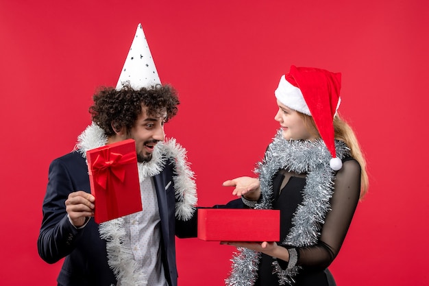 Giovani coppie che aprono il nuovo anno presente sul pavimento rosso festa di natale d'amore