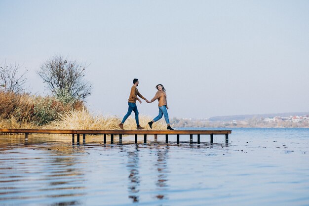 Young couple in park standing by the river standing on the deck bridge