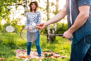 Young couple playing badminton on picnic