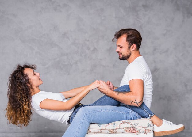 Free photo young couple playing on chair