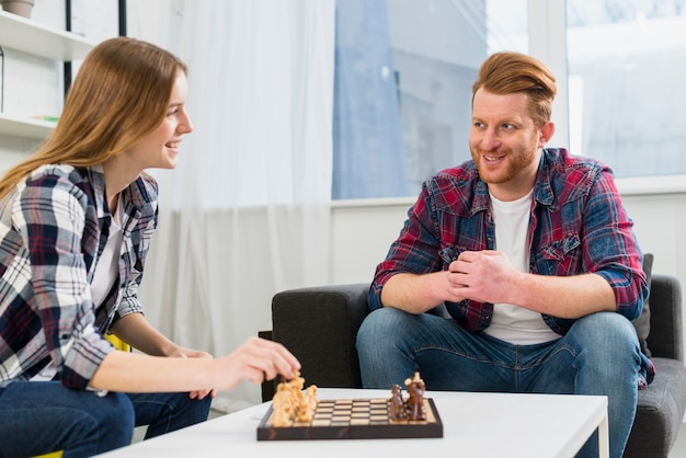 Молодая пара играет на шахматной доске в гостиной дома