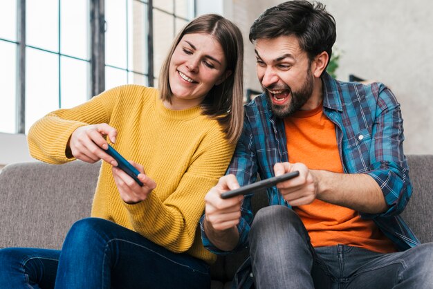 若いカップルが携帯電話でビデオゲームをプレイ プレミアム写真
