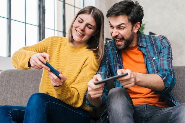 若いカップルが携帯電話でビデオゲームをプレイ プレミアム写真 若いカップルが携帯電話でビデオゲームをプレイ プレミアム写真