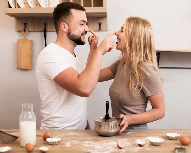 台所で小麦粉と遊ぶ若いカップル