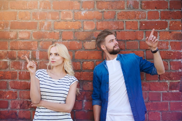 Young couple pointing on the brick wall